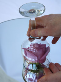 diy-candle-centerpiece-3 a purple rose being placed under a wine glass for a centerpiece